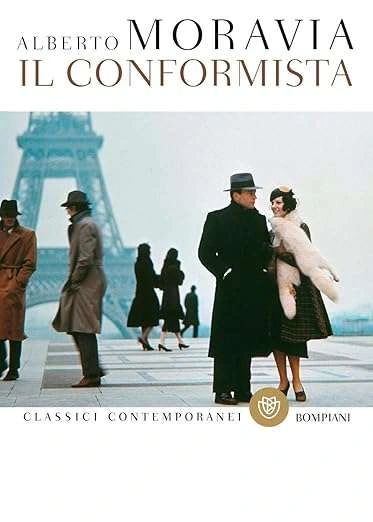 una fotografia in stile vintage di un uomo in cappotto scuro e cappello che cammina a braccetto con una donna con una stola di pelliccia davanti alla Torre Eiffel, con altri pedoni sullo sfondo.